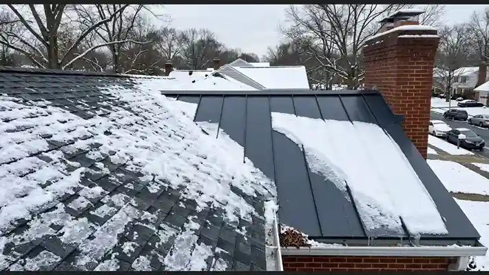 Close-up of adjacent residential roof slopes showing snow clinging to asphalt shingles while ice slides cleanly off metal panels.